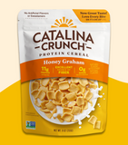 A package of Catalina Crunch Protein Cereal in Honey Graham flavor. The packaging is predominantly white and yellow, with an image of the cereal pieces on the front.