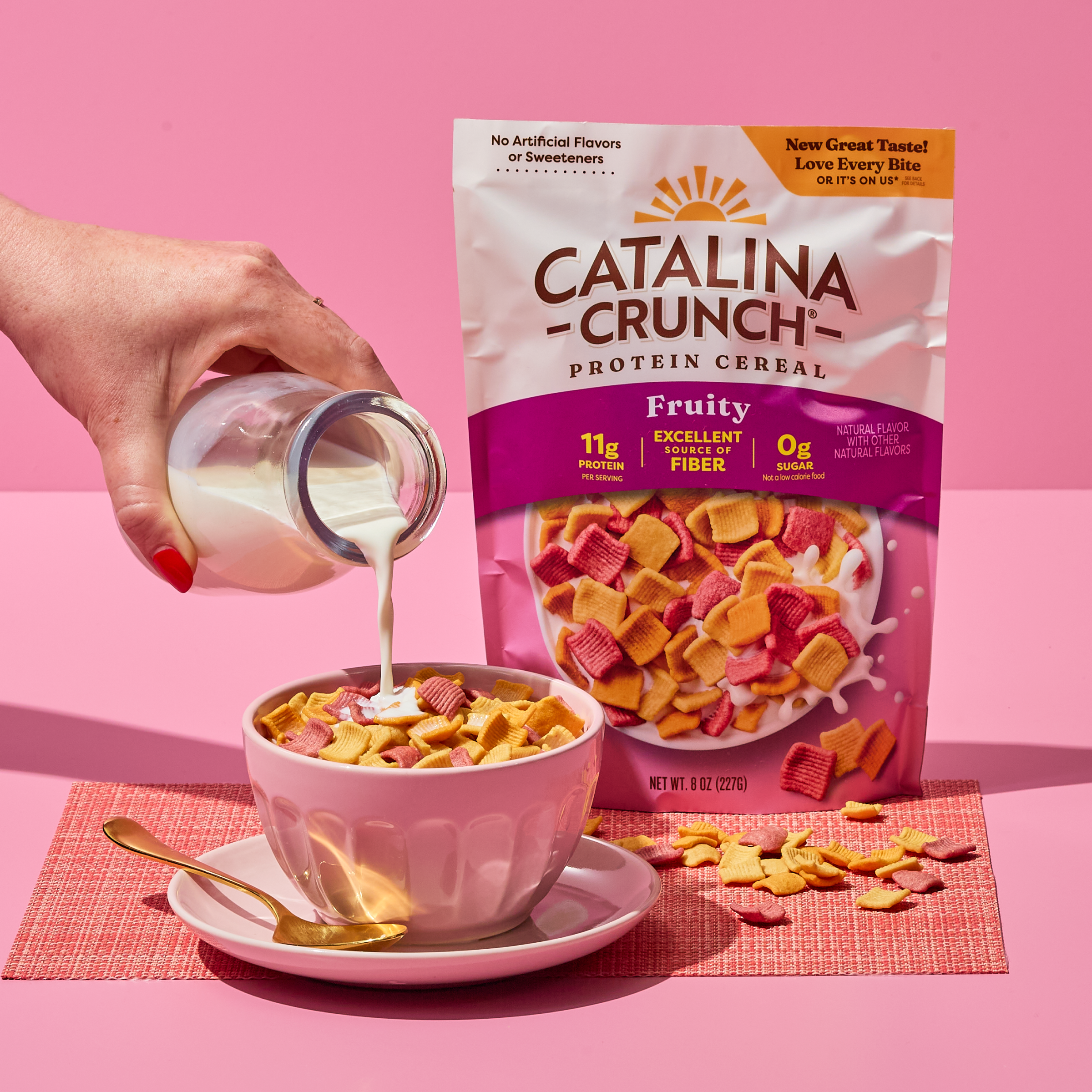 Catalina Crunch Protein Cereal being poured into a bowl with a pink background