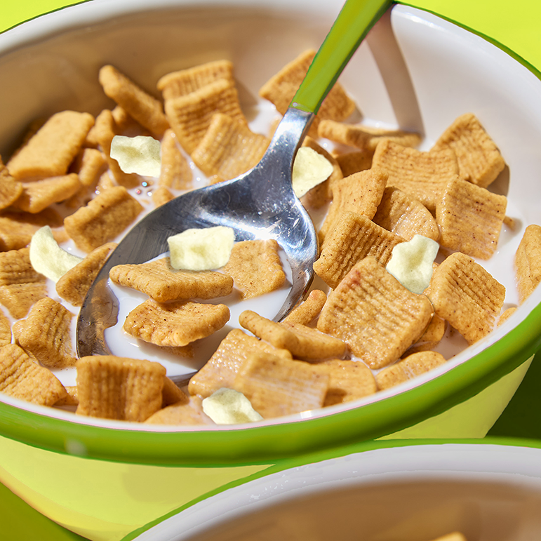 Bowl of cereal with a spoon featuring real apple pieces.