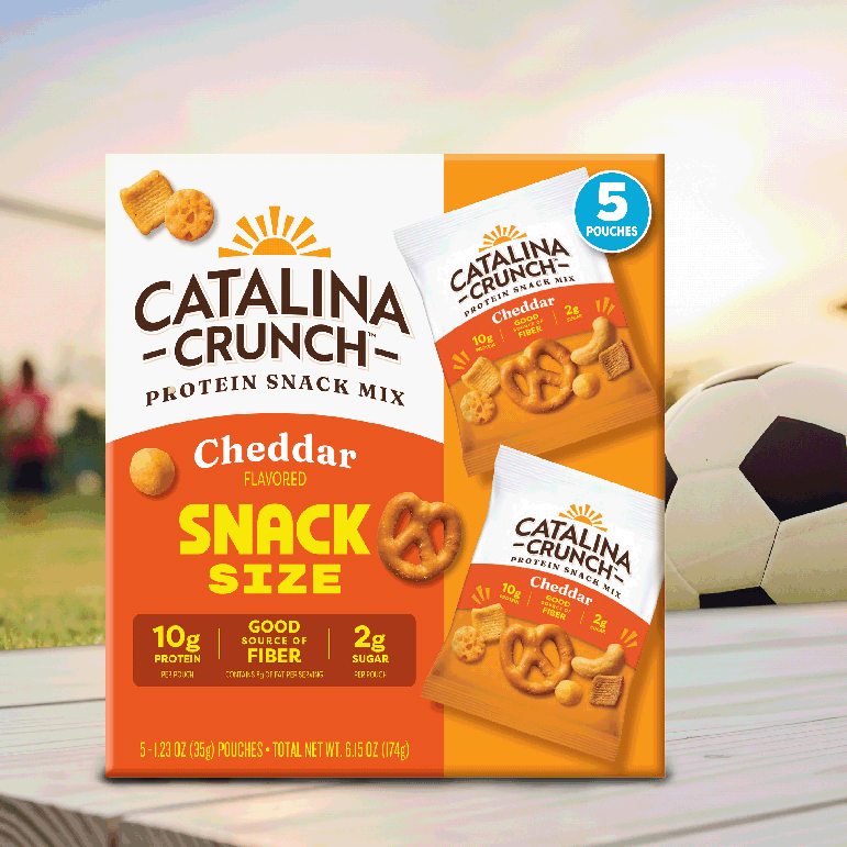 Catalina Crunch Cheddar flavored protein snack mix packaging on a blurred sports field background
