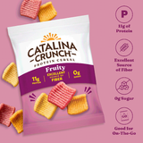 Catalina Crunch Protein Cereal package on a pink background with cereal pieces around