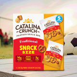 Catalina Crunch Protein Snack Mix packaging on a table with sports equipment in the background