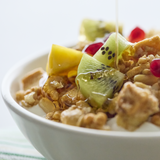 Bowl of cereal with fruit and syrup on a white background
