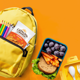 Yellow backpack with school supplies and a lunchbox with a sandwich, carrots, and grapes on an orange background.