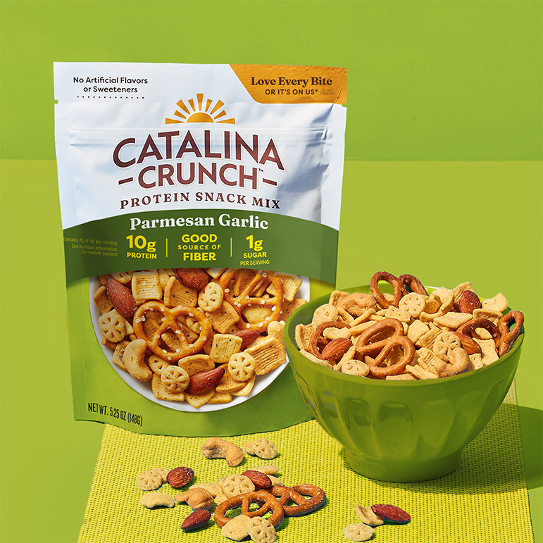 Catalina Crunch Parmesan Garlic protein snack mix packaging with a bowl of snack mix on a green background