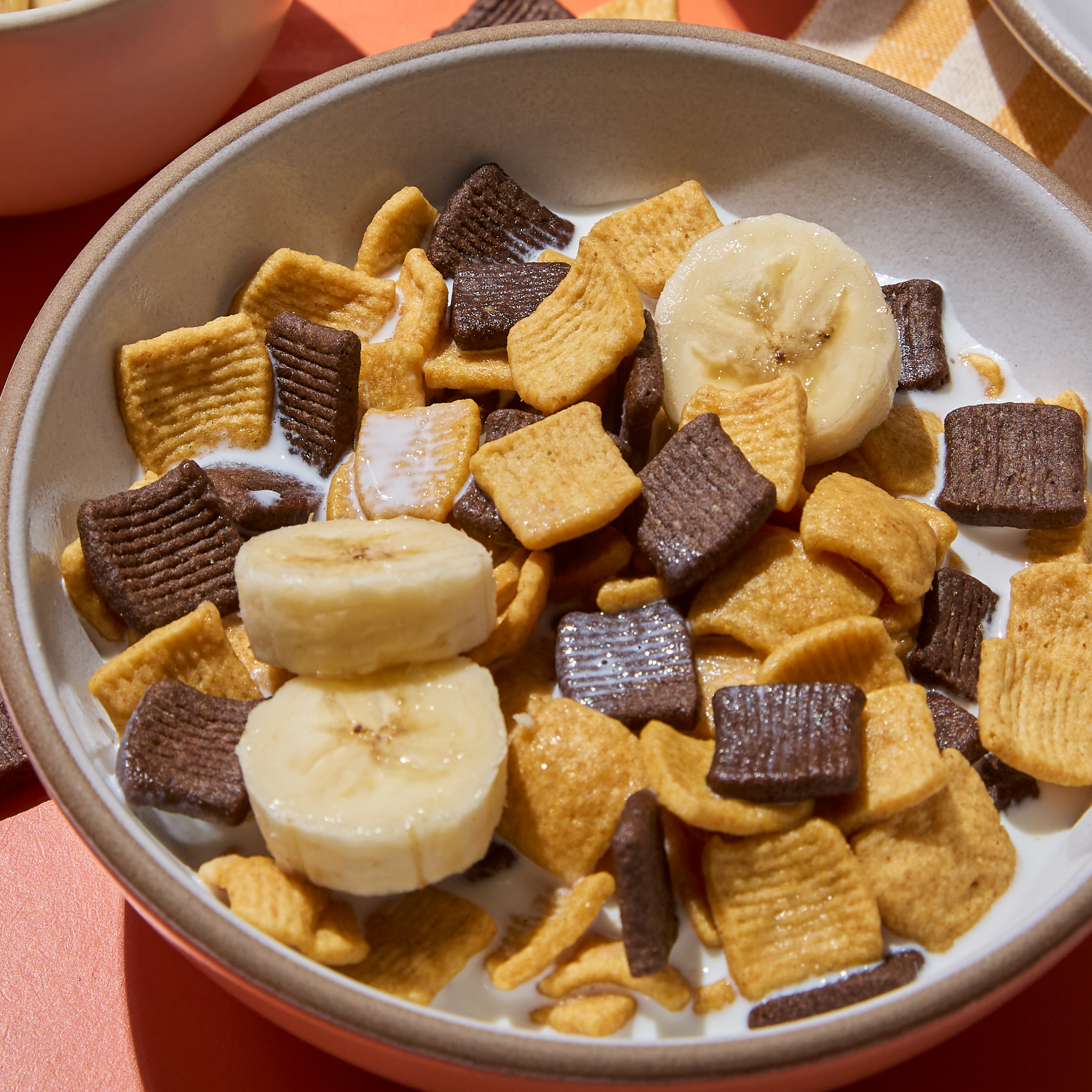 Bowl of cereal with chocolate and banana pieces on a red background