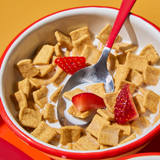Bowl of cereal with milk and strawberries on a yellow background