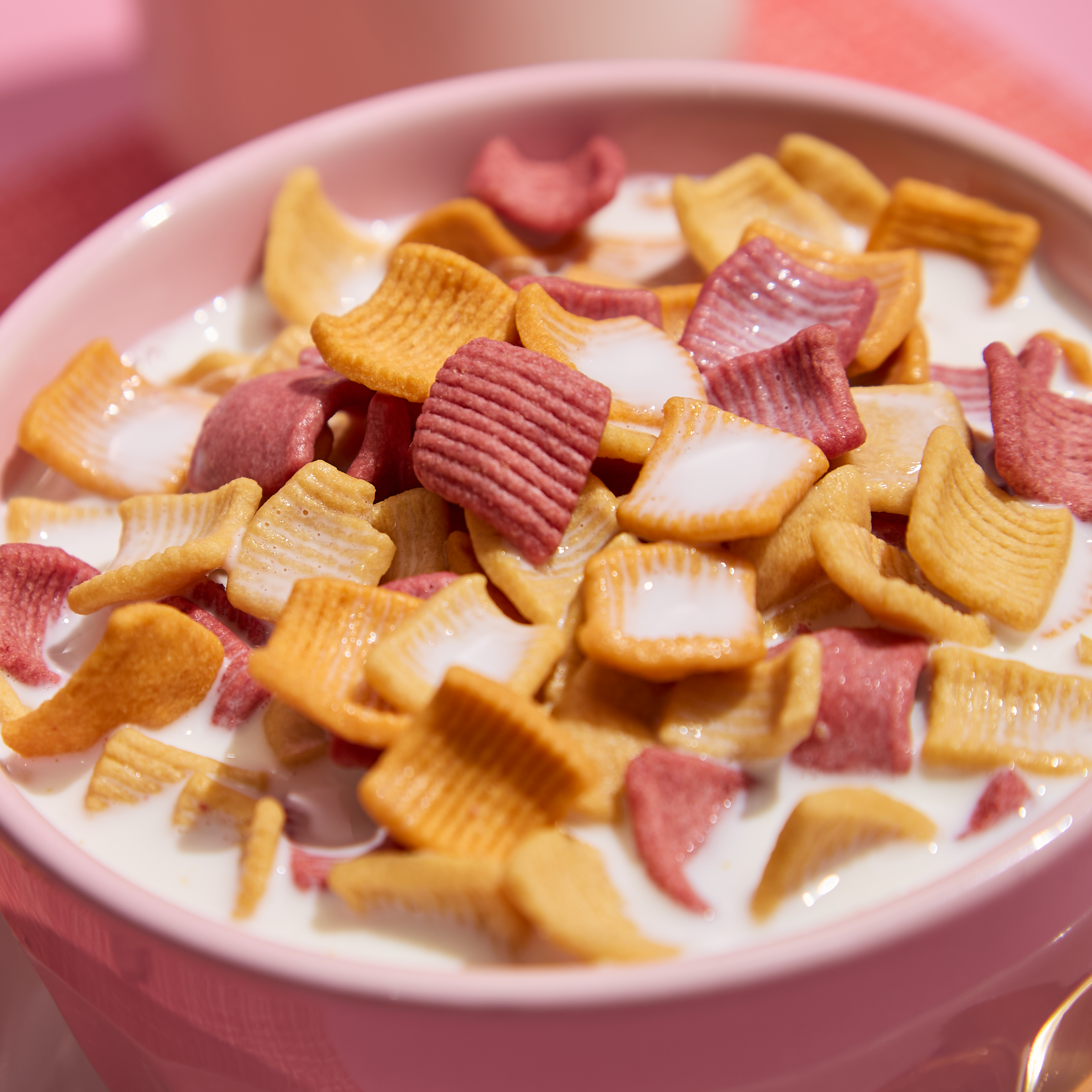 Colorful cereal in a pink bowl with milk