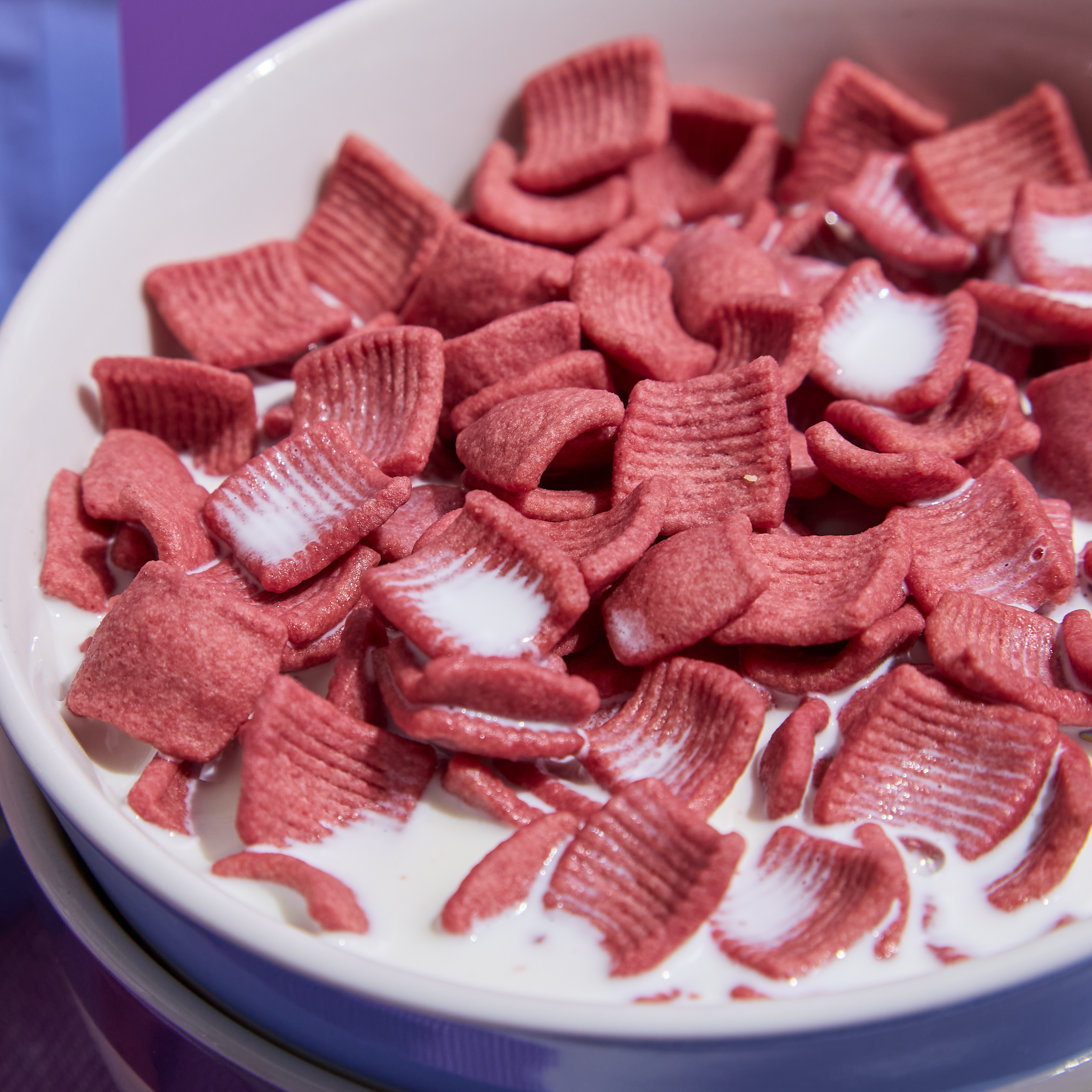 Red cereal pieces in a bowl with milk