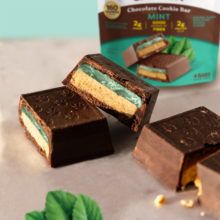 Chocolate cookie bar with mint filling on a light surface, with packaging in the background.