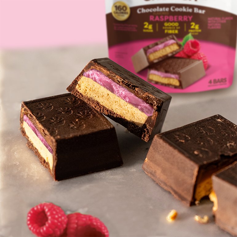 Chocolate cookie bars with raspberry filling on a gray surface, with packaging in the background.